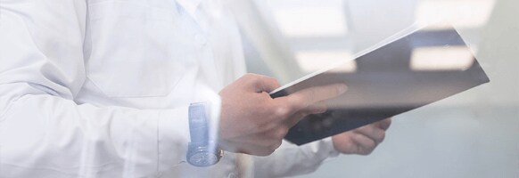 Un homme portant un sarrau de laboratoire tient un carnet.